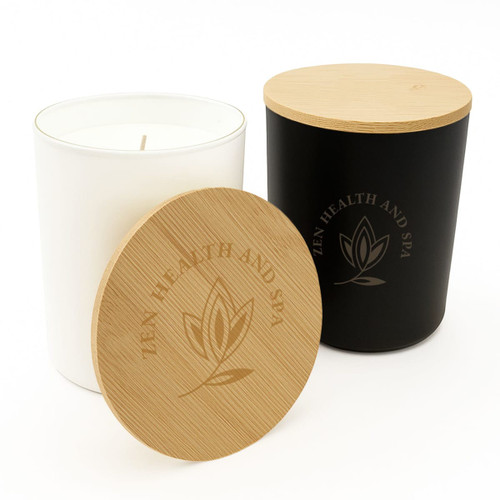 A large glass candle in black with a wooden lid, featuring an engraved logo design. The candle itself is white. A large glass candle in black with a wooden lid, featuring an engraved logo design. The candle itself is white.