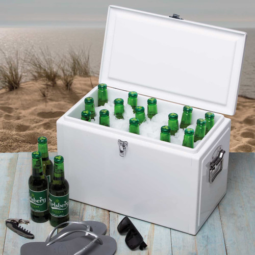 A white cooler box filled with green bottles of beer, sitting on a sandy beach with sunglasses and a bottle opener nearby.