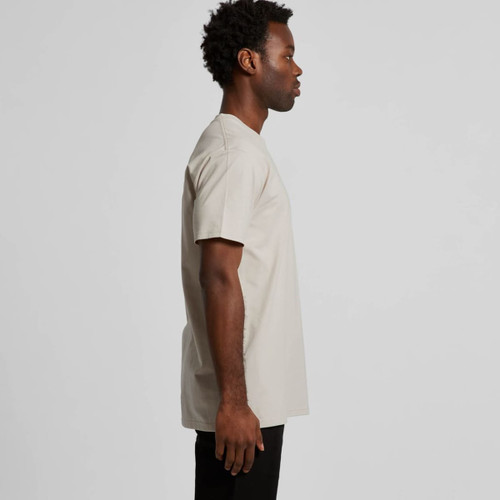 A side view of a beige Staple Tee T-shirt on a model, featuring short sleeves and a simple design. A side view of a beige Staple Tee T-shirt on a model, featuring short sleeves and a simple design.