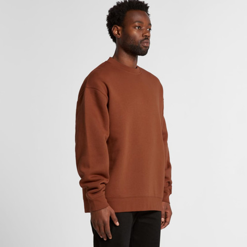 A man wearing a brown sweater stands sideways, showcasing the relaxed fit and style of the garment. A man wearing a brown sweater stands sideways, showcasing the relaxed fit and style of the garment.