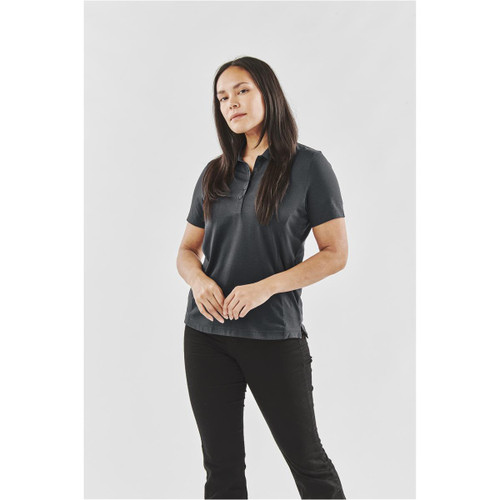 A woman wearing a black Women's Settebello Polo shirt, standing against a plain background, with a logo on the shirt.