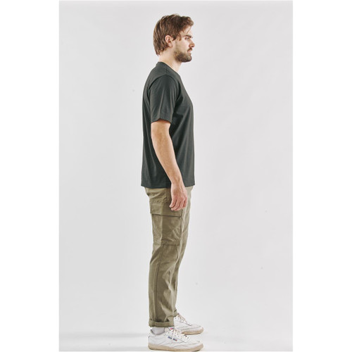 A side view of a man wearing a black Men's Settebello Tee paired with olive green trousers and white sneakers.