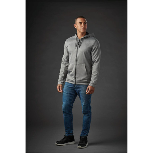 A grey zip-up hoody with a hood, paired with blue jeans, worn by a model against a dark background. A grey zip-up hoody with a hood, paired with blue jeans, worn by a model against a dark background.