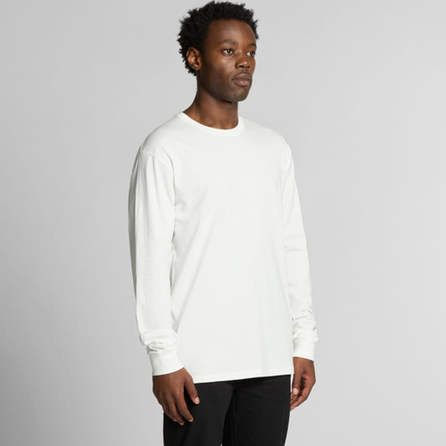 A man wearing a long-sleeve white t-shirt, standing against a plain background. The shirt features a logo. A man wearing a long-sleeve white t-shirt, standing against a plain background. The shirt features a logo.