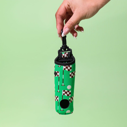 A green neoprene golf ball sleeve featuring a quirky pattern with golf flags and holes, held by a hand. A green neoprene golf ball sleeve featuring a quirky pattern with golf flags and holes, held by a hand.