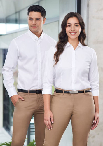 A white long sleeve shirt on a male and female model, paired with beige trousers. The shirt has a collar and buttons. A white long sleeve shirt on a male and female model, paired with beige trousers. The shirt has a collar and buttons.