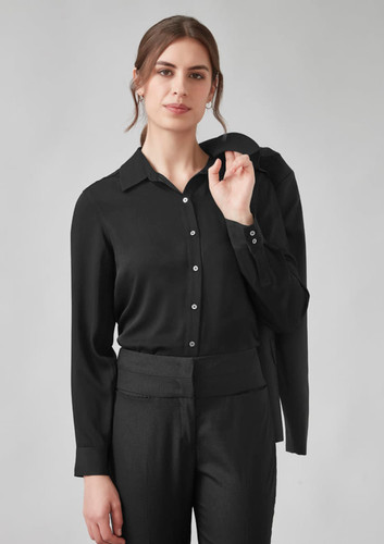 A woman wearing a black long sleeve shirt, holding a blazer over her shoulder, paired with black trousers. A woman wearing a black long sleeve shirt, holding a blazer over her shoulder, paired with black trousers.