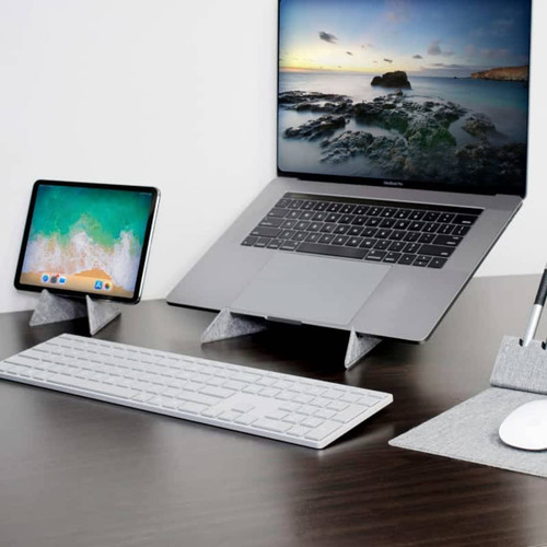 A grey eco laptop stand displaying a laptop and tablet, alongside a sleek keyboard and mouse on a matching mat. A grey eco laptop stand displaying a laptop and tablet, alongside a sleek keyboard and mouse on a matching mat.
