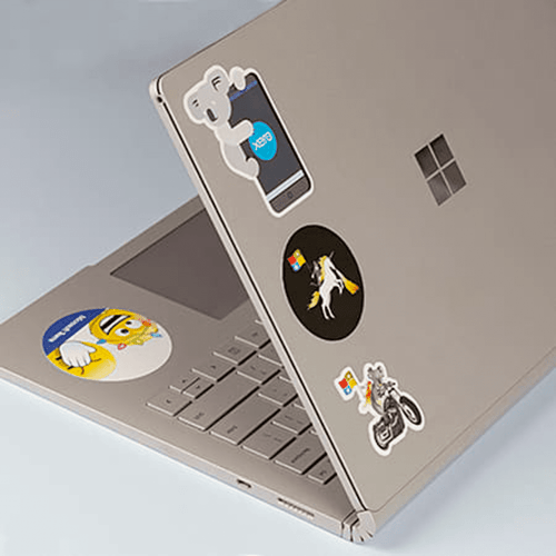 A silver laptop covered in various colourful stickers, including cartoon characters and logos.