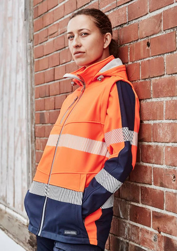 A women's softshell jacket in bright orange and navy, featuring reflective strips and a logo. A women's softshell jacket in bright orange and navy, featuring reflective strips and a logo.