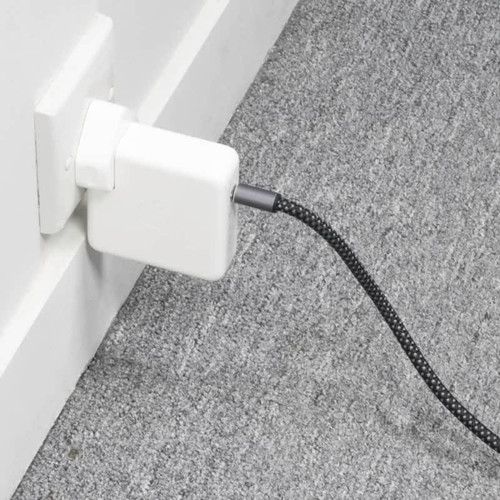 A white charger plugged into a wall socket, with a black and silver charging cable extending from it. A white charger plugged into a wall socket, with a black and silver charging cable extending from it.