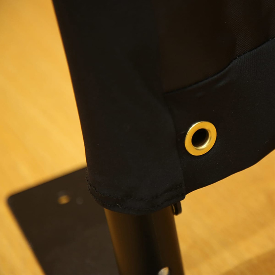 A black sidewalk cafe barrier featuring a grommet for attachment, set against a wooden surface.