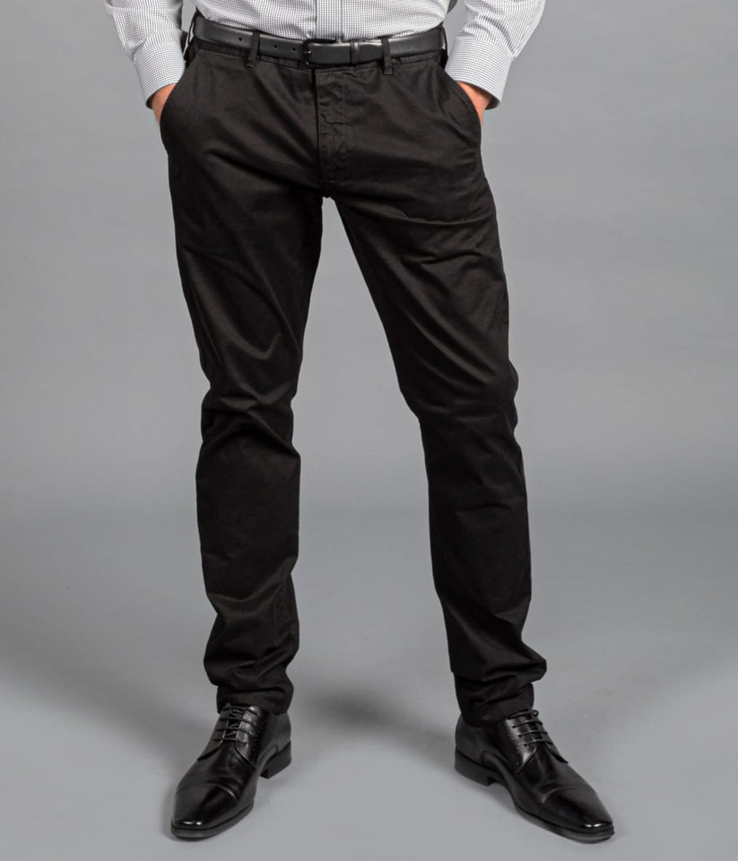 A pair of black chinos worn with a grey shirt and black shoes, featuring a subtle logo on the waistband.