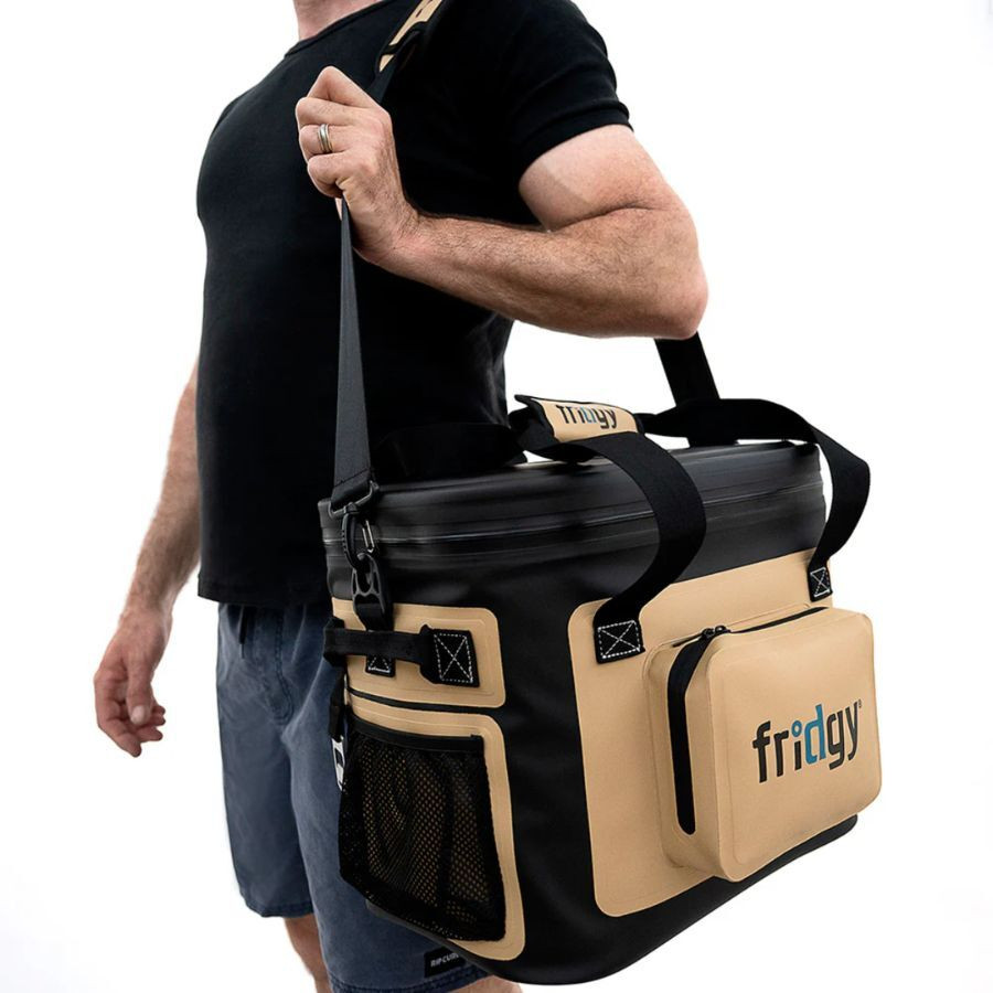 Man carrying a Fridgy insulated cooler bag with shoulder strap, ideal for outdoor adventures.