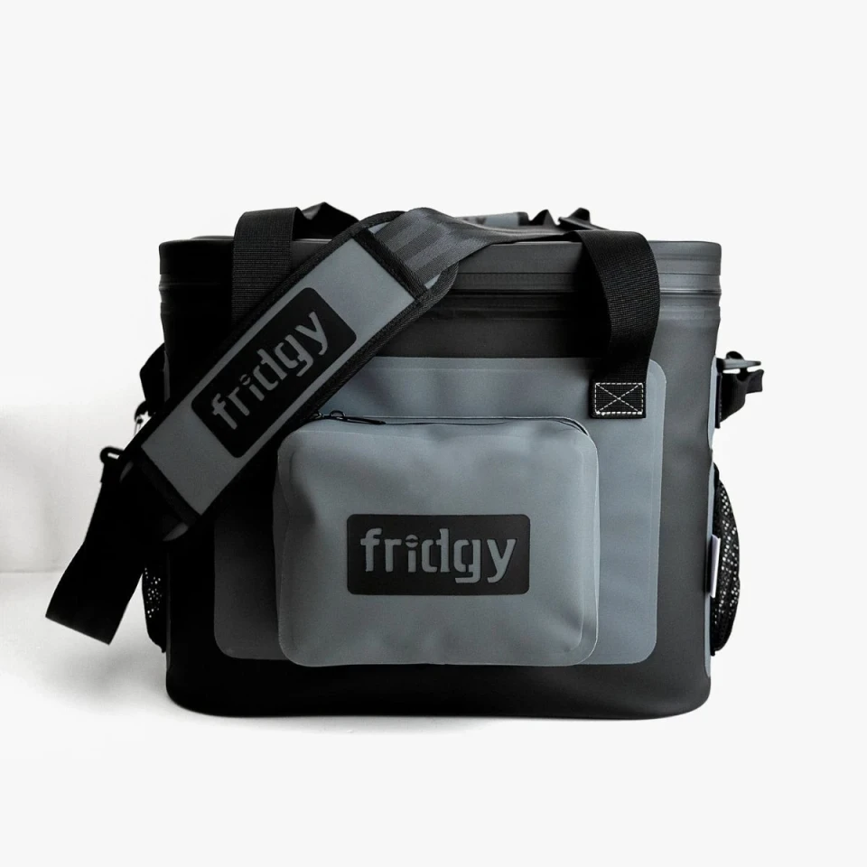 Front view of the Fridgy 20L cooler bag in grey and black, showcasing a waterproof front pocket, padded branded shoulder strap, and durable insulated construction.