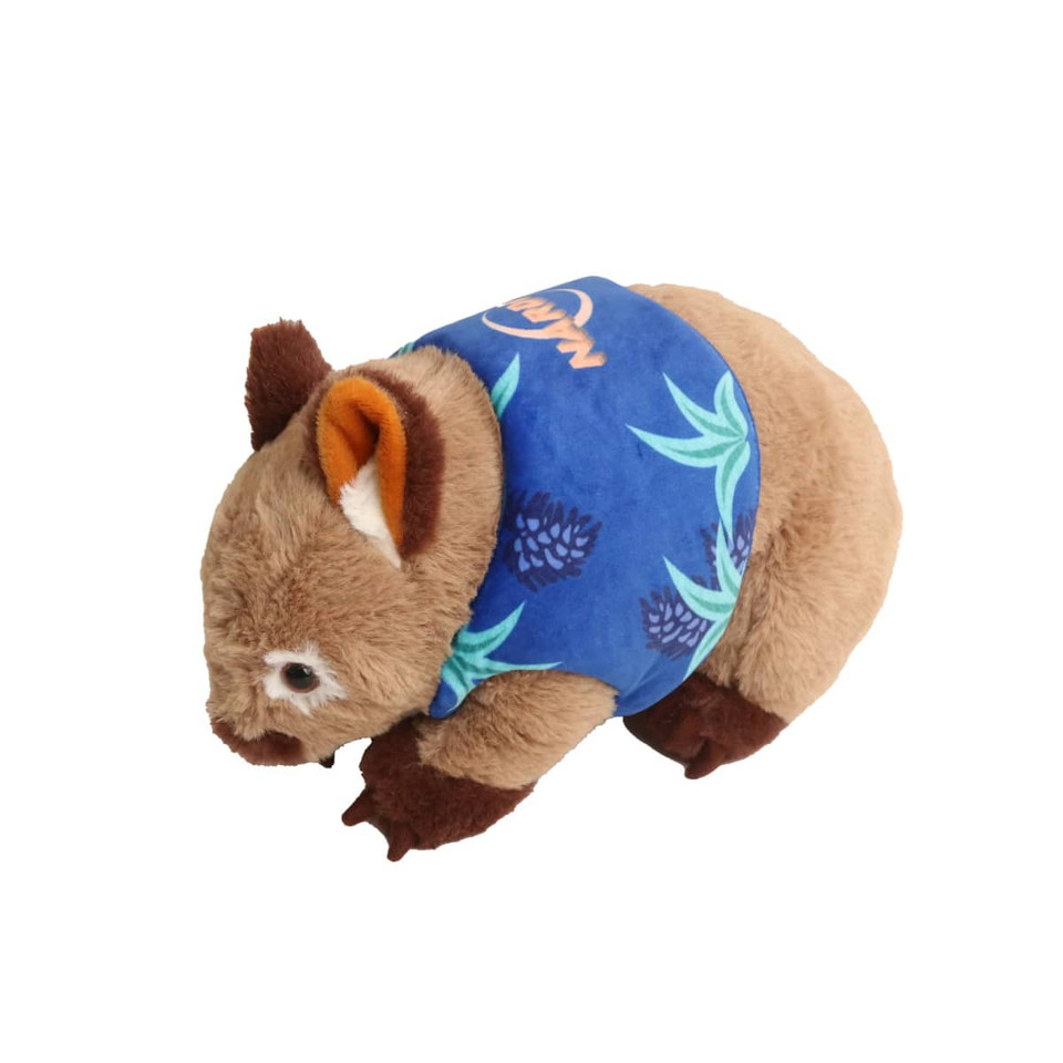 A brown wombat plush toy wearing a blue shirt with a leaf pattern, featuring a small logo.