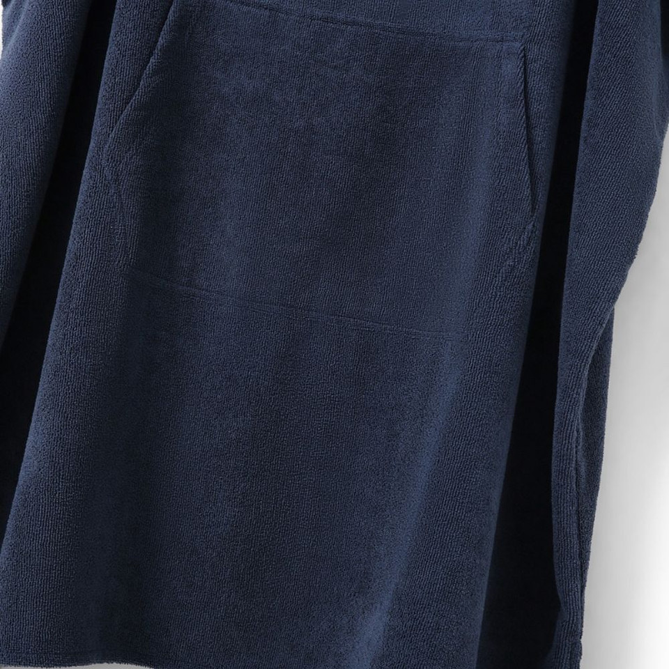 Navy blue terry cloth robe with pockets hanging on a white wall.