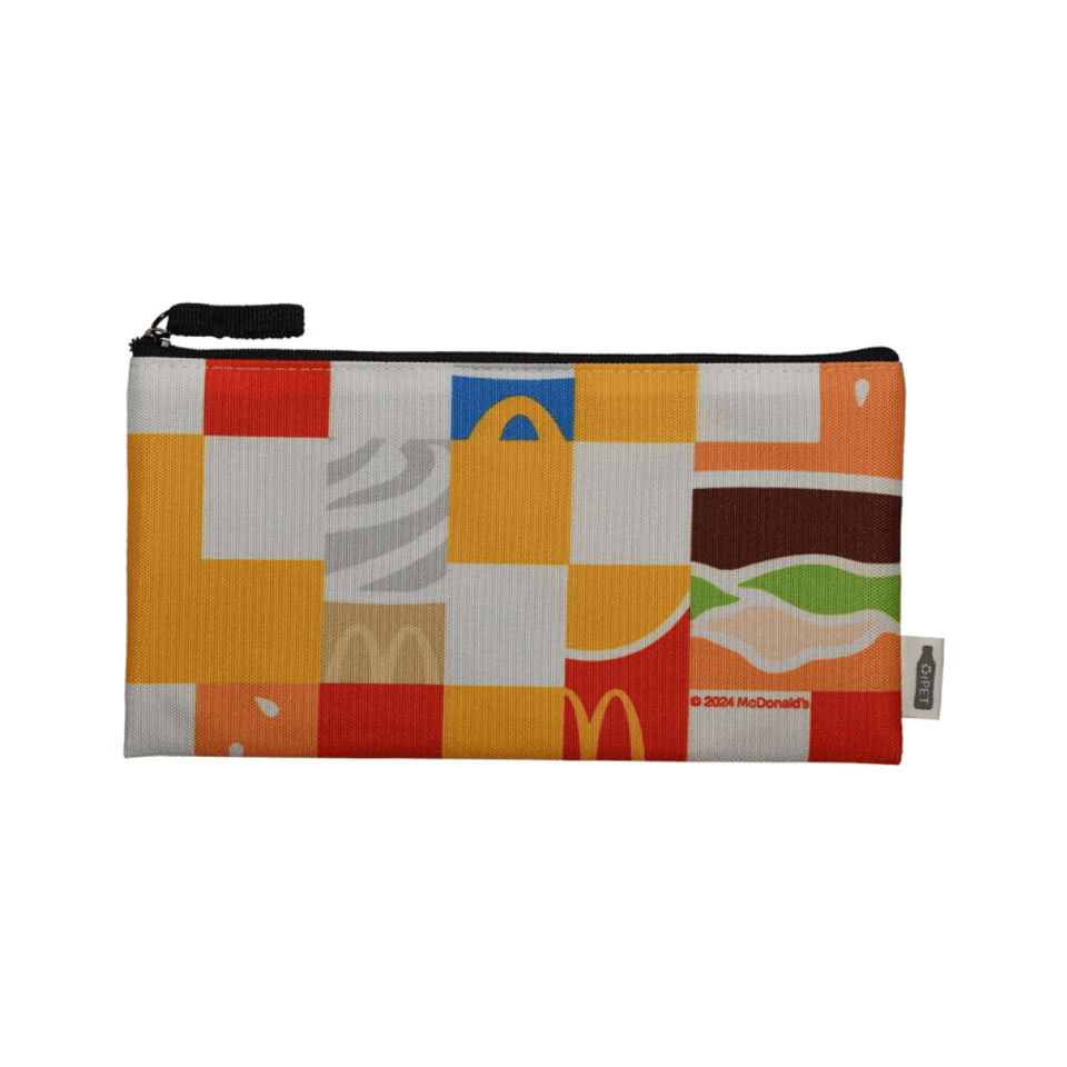 A colourful pouch featuring various block patterns, including iconic food motifs and a logo, with a black zipper.