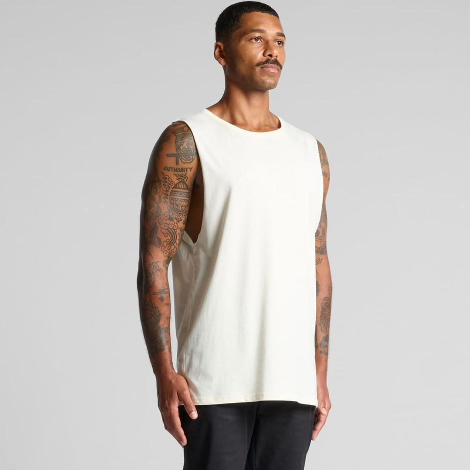 A light-coloured singlet tank top displayed on a model with tattoos, featuring a simple design and no visible branding.