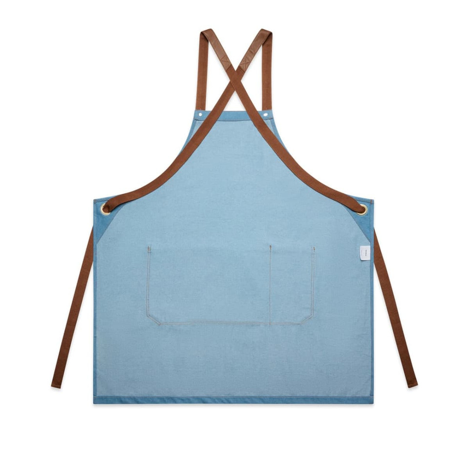 A denim apron in light blue with brown straps and a front pocket, featuring a small logo.