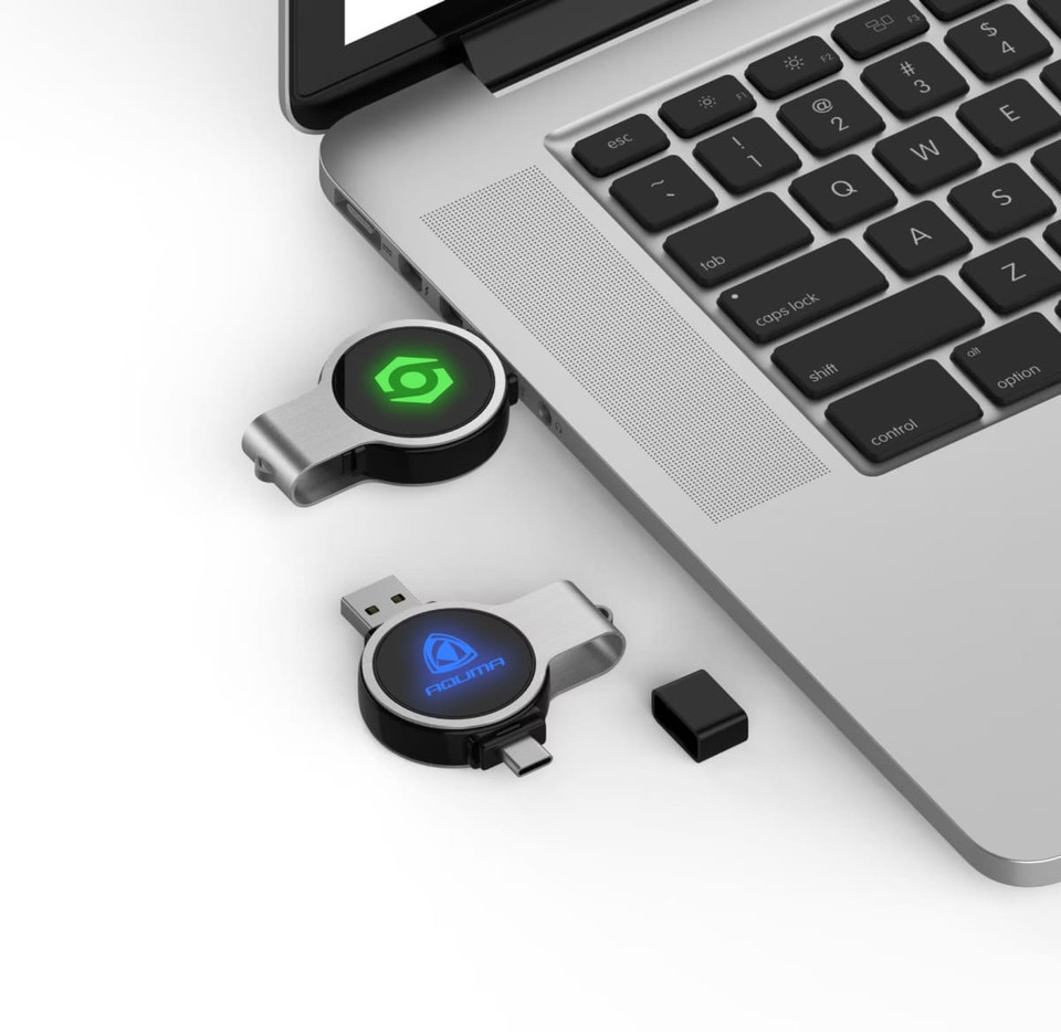 Double ended swivel flash drives in black and silver, featuring a logo, placed beside a laptop keyboard.