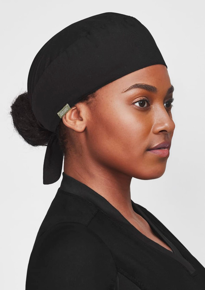 A black unisex reversible scrub cap worn by a person, featuring a logo on the side.
