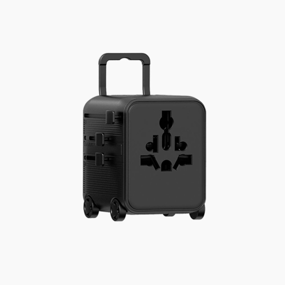 A black travel plug adapter with a handle and wheels, featuring multiple ports on the front.