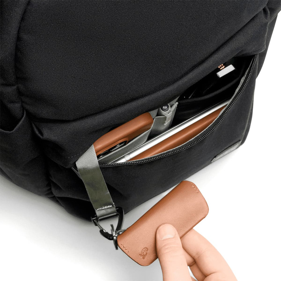 A black backpack with a brown leather key holder visible in an unzipped pocket.