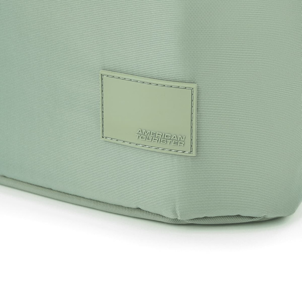 A green tote bag with a textured surface and a branded tag. The bag has a structured shape and sturdy construction.