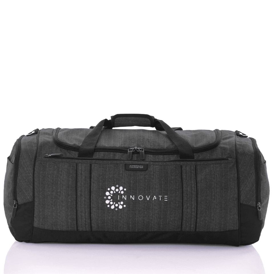 A grey duffle bag with black accents and a logo, featuring multiple zippered compartments and sturdy handles.