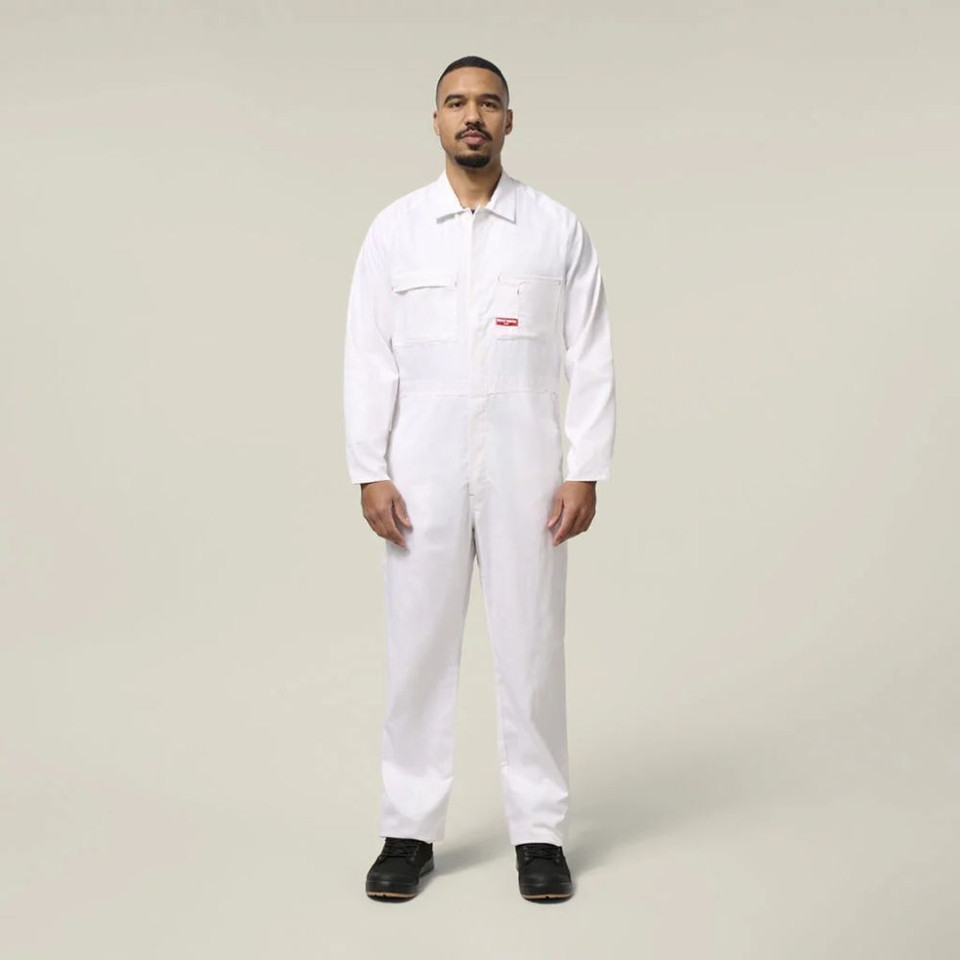 Male model wearing a white work jumpsuit and black work boots against a neutral background.