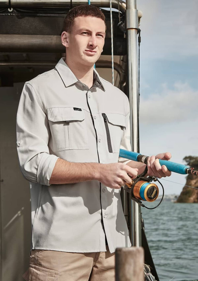 A light grey long sleeve button-up shirt with two chest pockets, worn by a man holding a fishing rod by the water.