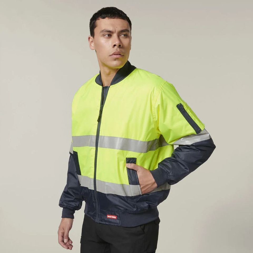 Man wearing yellow high visibility safety jacket with reflective stripes.
