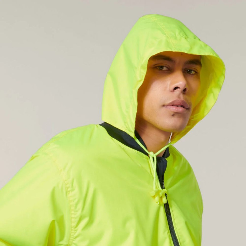 Man wearing neon yellow hooded jacket, looking to the side.