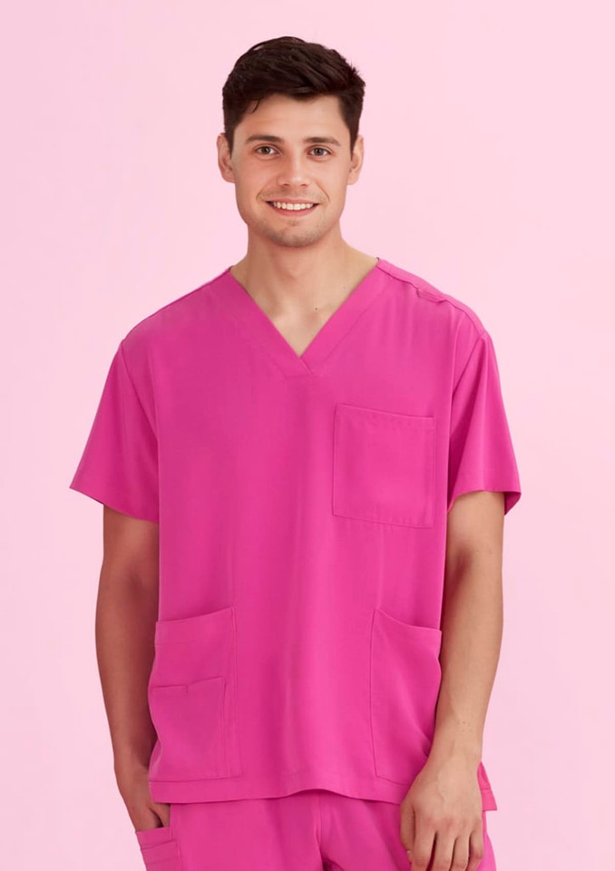 A unisex pink V-neck scrub top displayed on a model, featuring a pocket on the front and an overall bright colour.