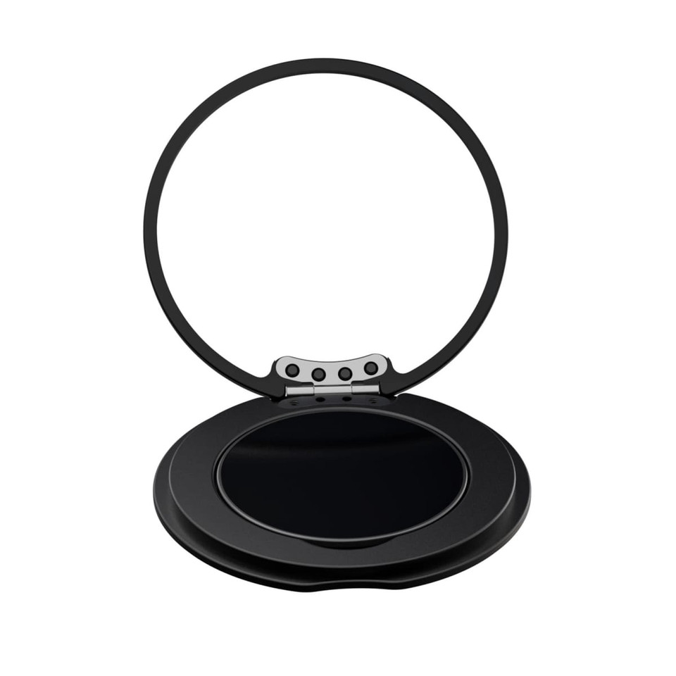 A black circular phone grip and stand with a hinged design, featuring a reflective surface inside.
