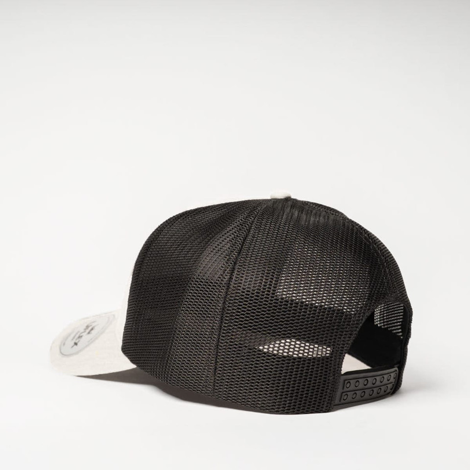 A trucker cap in black with a mesh back and a light-coloured brim, featuring a logo on the side.