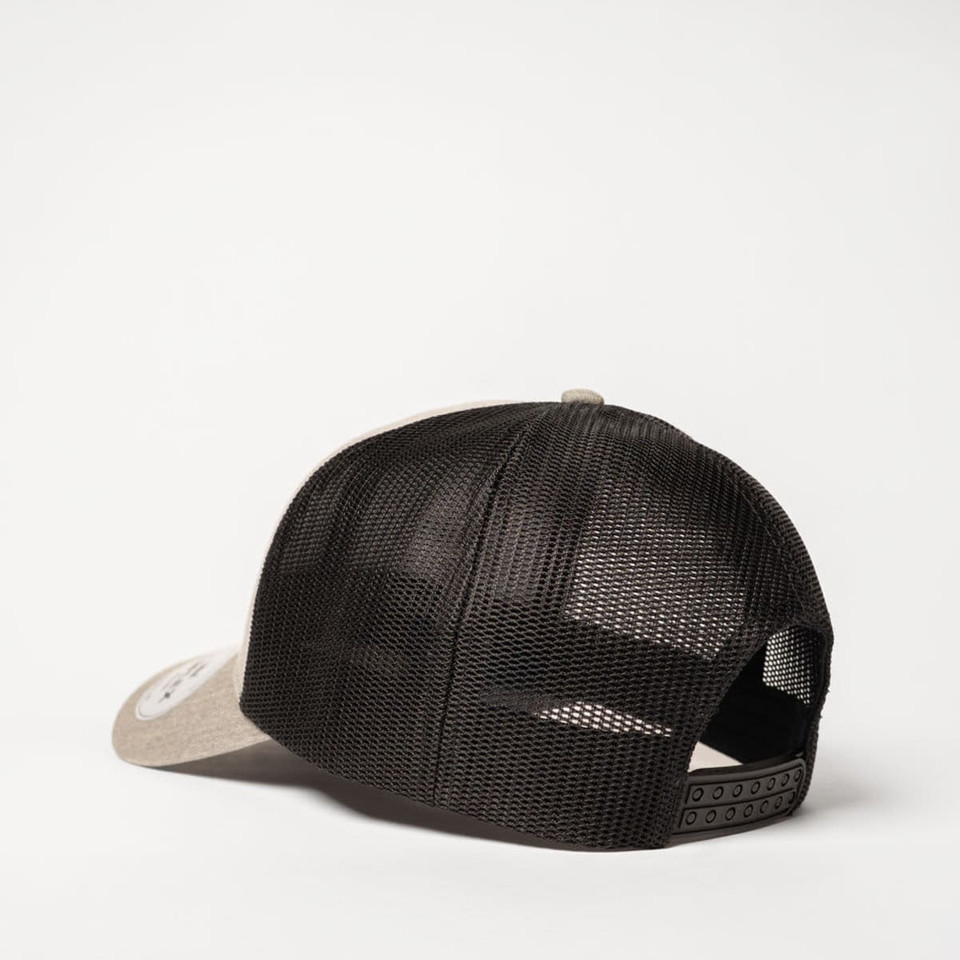 A trucker cap featuring a beige front with a black mesh back and a snap closure. It has a logo on the front.