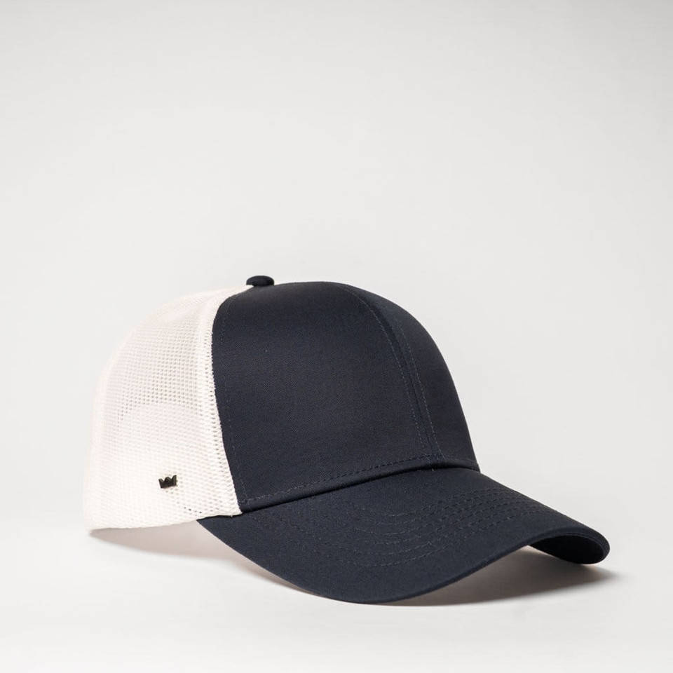 A navy and white UFlex Classic Ultra-lite 6 Panel Trucker Cap featuring a mesh back and a branded logo.
