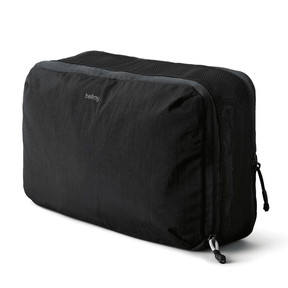 A black packing cube with a mesh panel, featuring a logo and a zipper closure.