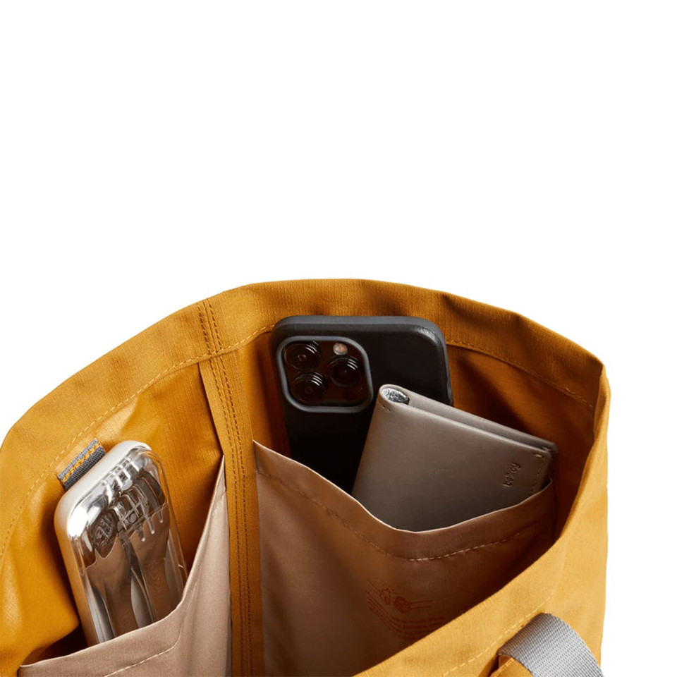 A yellow tote bag interior with two pockets holding a drink bottle and two smartphones.