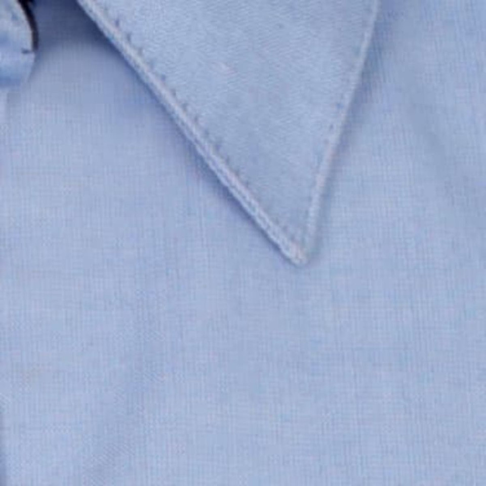 A light blue button-up shirt featuring a classic collar and a minor branding element.