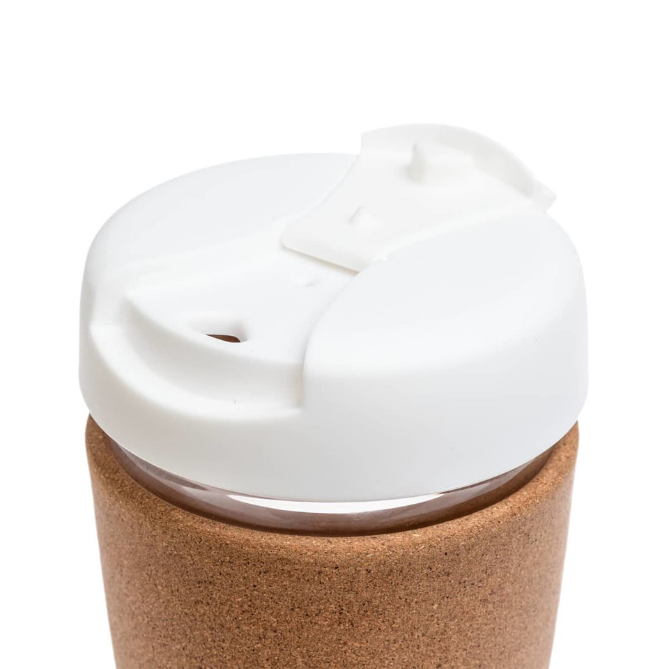 A reusable coffee cup featuring a cork band and a white lid with a sipping opening.