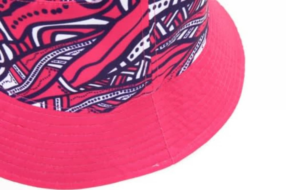 A reversible bucket hat featuring a vibrant pink and patterned design, with a textured brim and a logo.