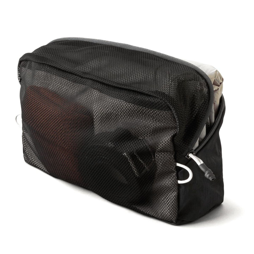 A black mesh packing cube containing various items, showcasing its organisational features and content visibility.