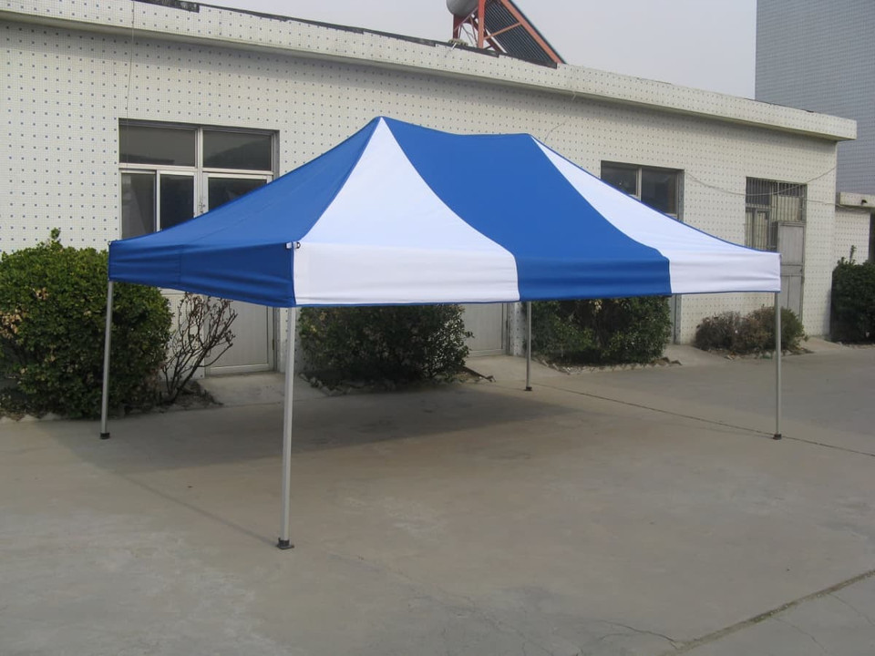 A blue and white marquee canopy tent with a frame, set up outdoors on a concrete surface.
