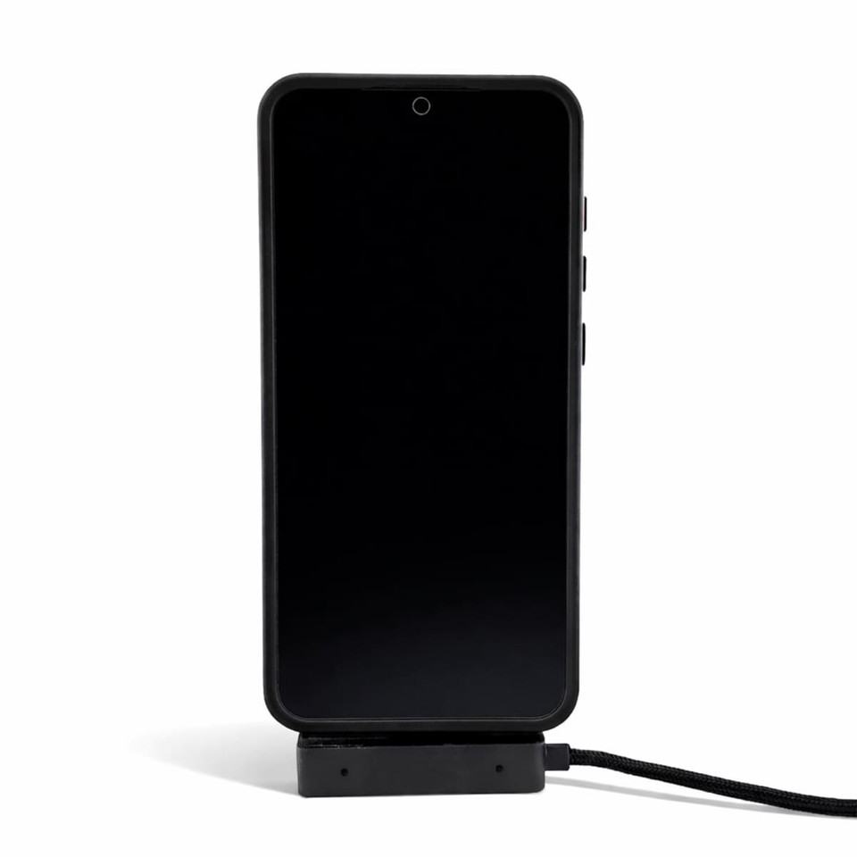 A black phone is displayed on a charger, connected by a charging cable. The charger has a sleek design.