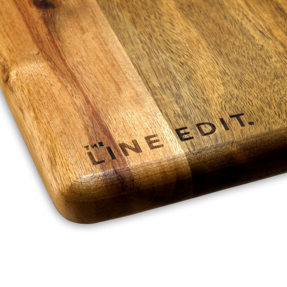 A wooden acacia serving board featuring a smooth finish and the brand logo engraved on one side.