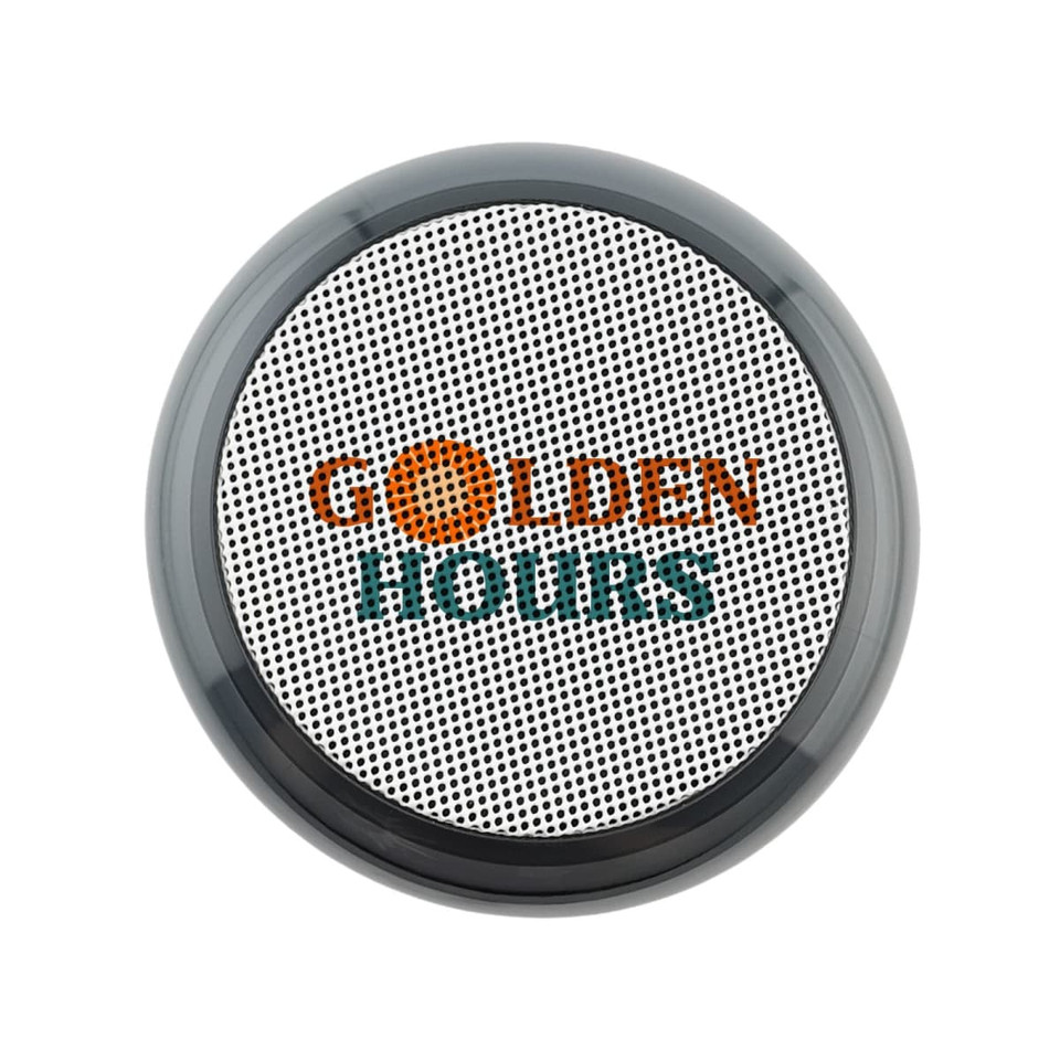 A round, black and silver speaker with a textured surface and a logo on the front.
