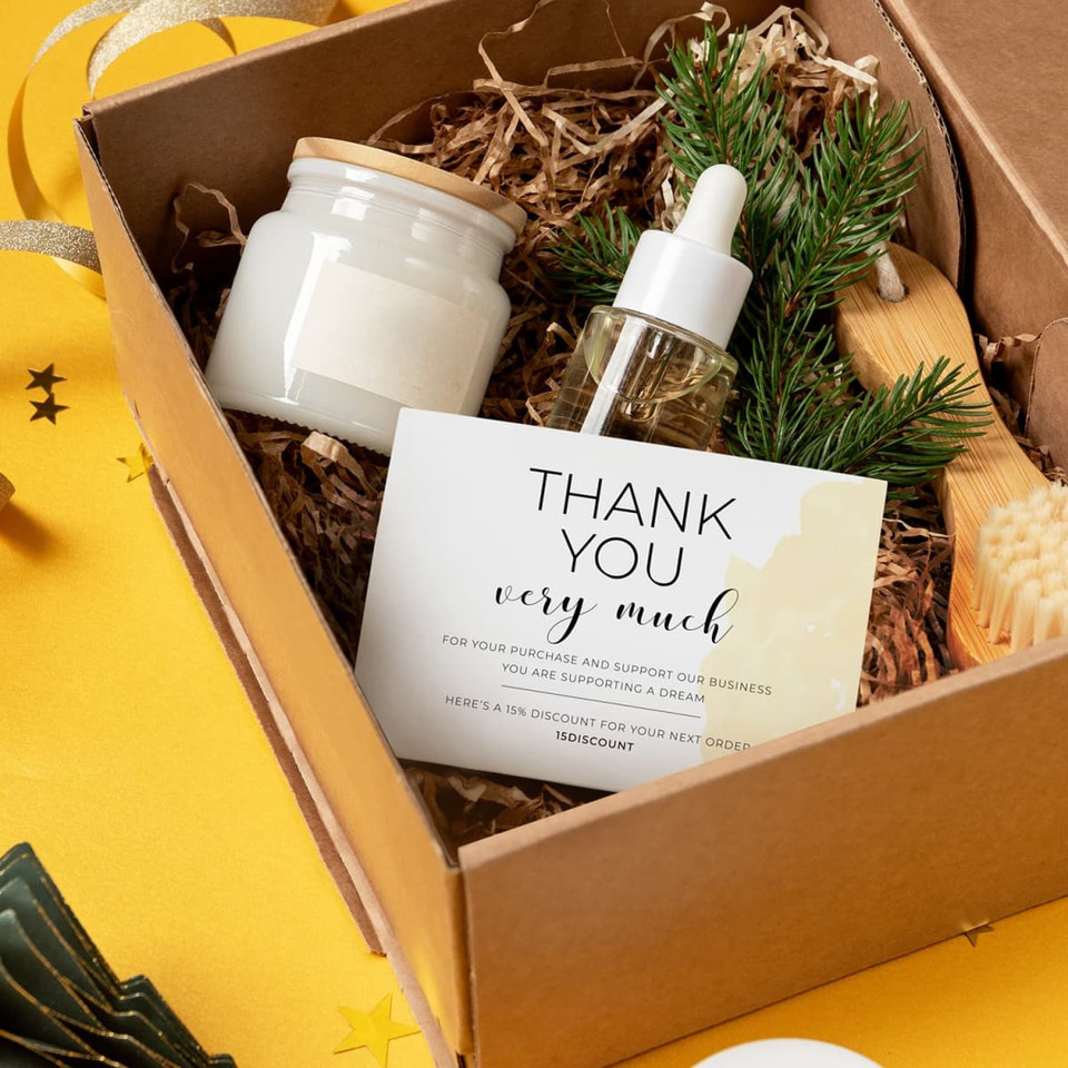 A gift box containing a jar, a dropper bottle, and a thank you card, surrounded by decorative fillers and greenery.